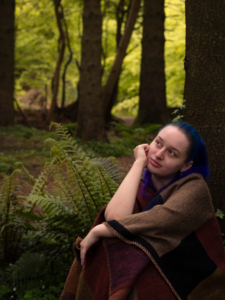 Shannon sitting in the woods looking into the distance.